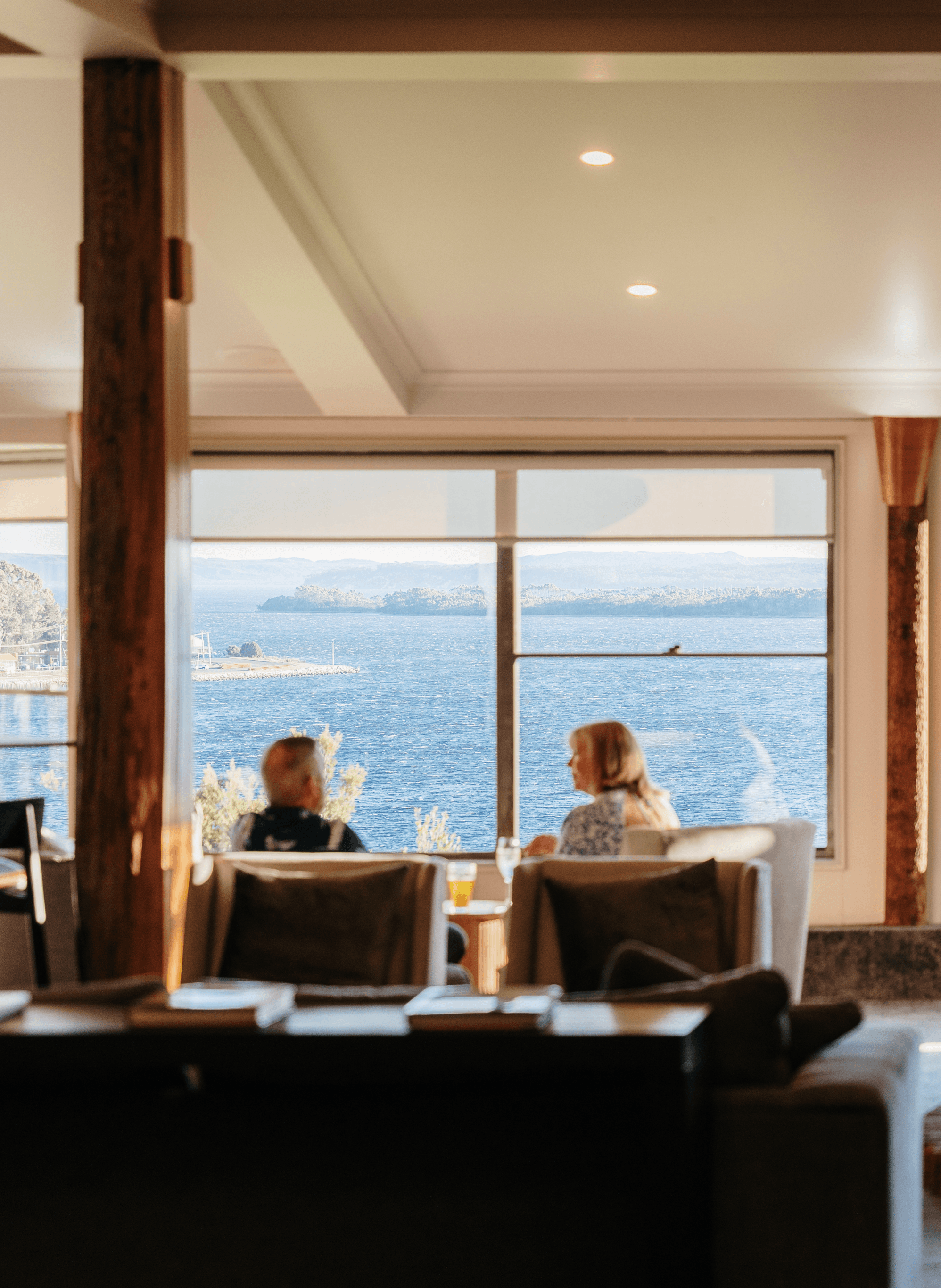 A couple having drinks at while looking out of the water in a hotel lounge